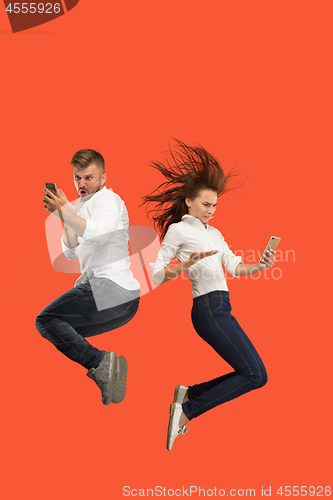 Image of Full length of young couple with mobile phone while jumping