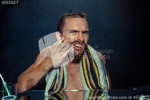 Image of Close up photo of young man looking for acnes on his face