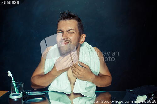 Image of Close up photo of young man looking for acnes on his face