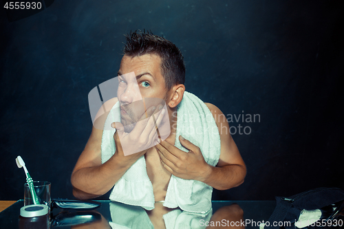 Image of Close up photo of young man looking for acnes on his face