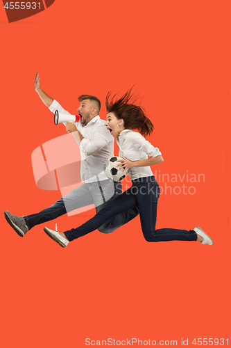 Image of The young man and woman as soccer football players kicking the ball at studio