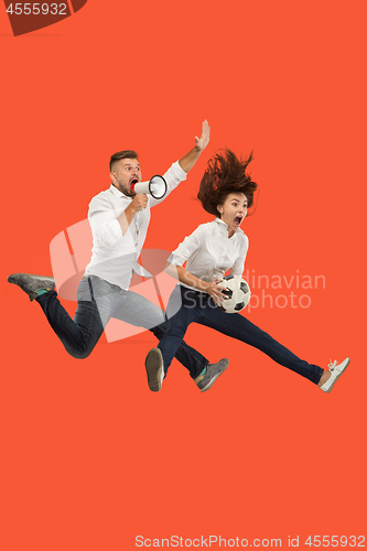 Image of The young man and woman as soccer football players kicking the ball at studio