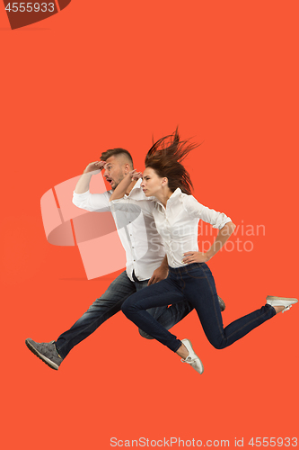 Image of Freedom in moving. Pretty young couple jumping against red background