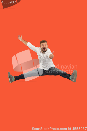 Image of Freedom in moving. handsome young man jumping against orange background