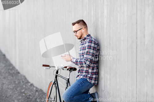 Image of hipster man in earphones with smartphone and bike