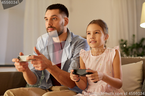 Image of father and daughter playing video game at home