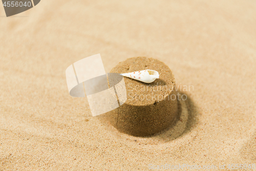 Image of sand shape made by mold with shell on summer beach