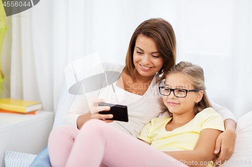 Image of happy mother and daughter with smartphone at home