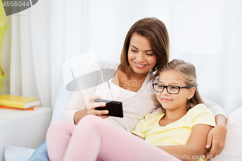 Image of happy mother and daughter with smartphone at home