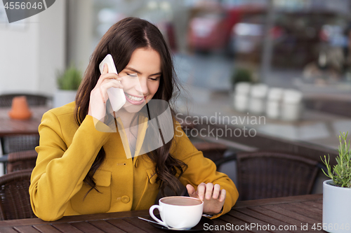 Image of teenage girl calling on smartphone at city cafe