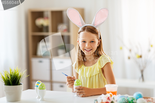 Image of happy girl coloring easter eggs at home