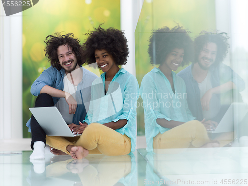 Image of multiethnic couple using a laptop on the floor