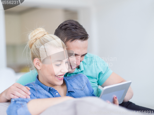 Image of couple relaxing at  home with tablet computers