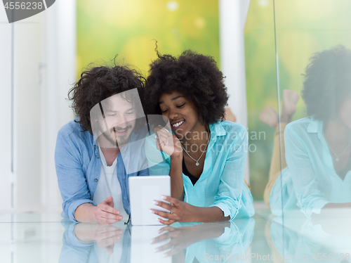 Image of Couple relaxing together at home with tablet computer