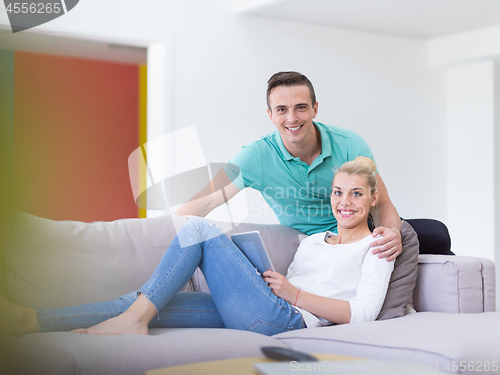 Image of couple relaxing at  home with tablet computers