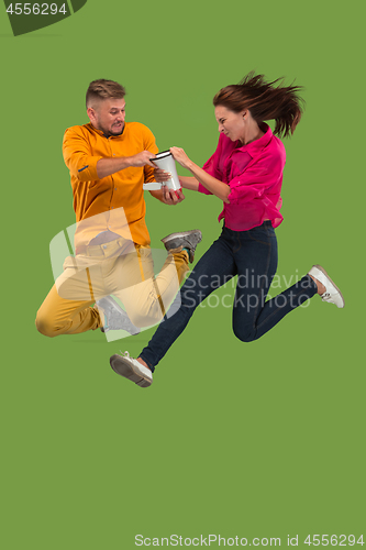 Image of Beautiful young couple jumping with megaphone isolated over green background