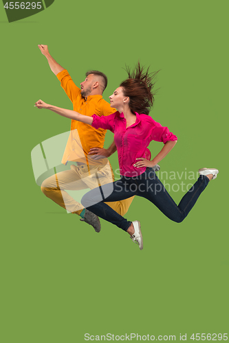 Image of Freedom in moving. Pretty young couple jumping against green background