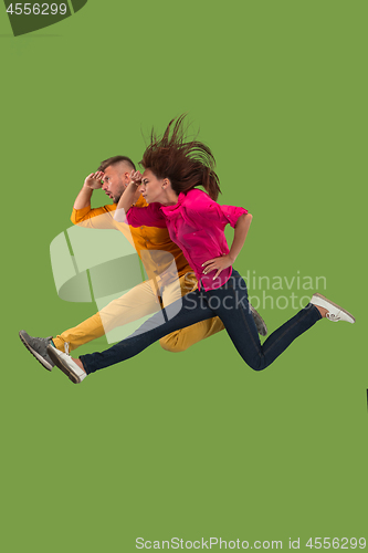 Image of Freedom in moving. Pretty young couple jumping against green background