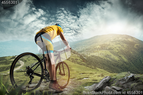 Image of The young fit men in helmet conquering mountains on a bicycle.