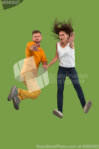 Image of Freedom in moving. Pretty young couple jumping against green background