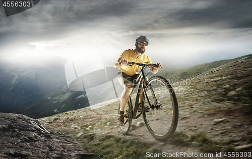 Image of The young fit men in helmet conquering mountains on a bicycle.