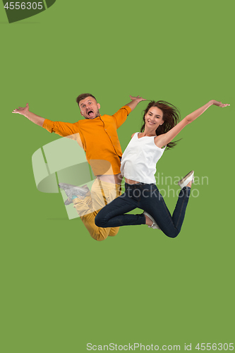 Image of Freedom in moving. Pretty young couple jumping against green background