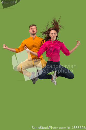 Image of Freedom in moving. Pretty young couple jumping against green background
