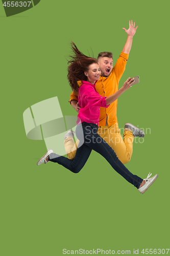 Image of Full length of young couple with mobile phone while jumping