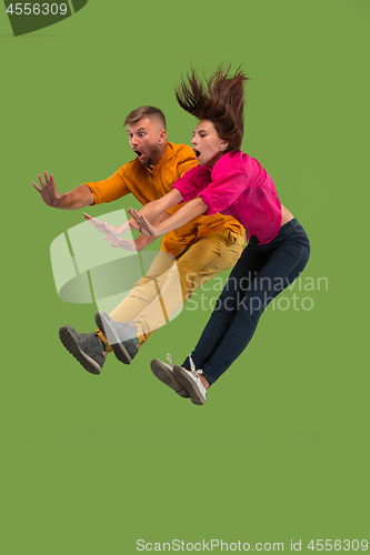 Image of Freedom in moving. Pretty young couple jumping against green background