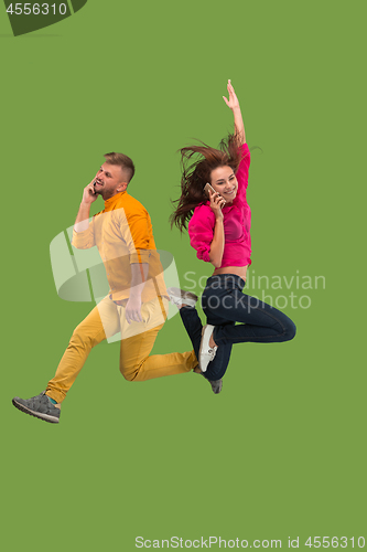 Image of Full length of young couple with mobile phone while jumping