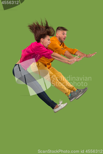 Image of Freedom in moving. Pretty young couple jumping against green background