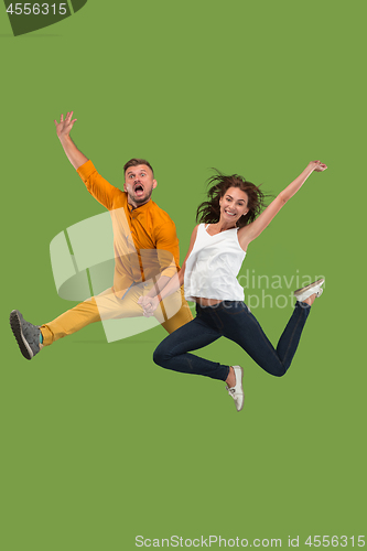 Image of Freedom in moving. Pretty young couple jumping against green background