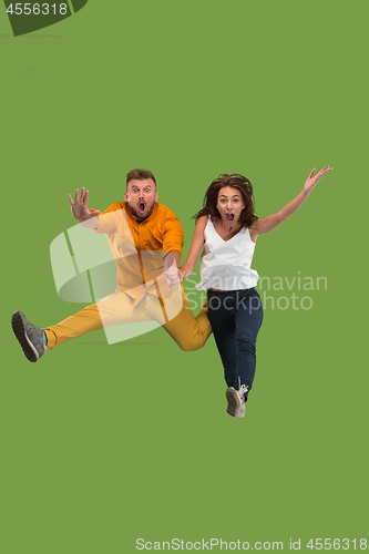 Image of Freedom in moving. Pretty young couple jumping against green background