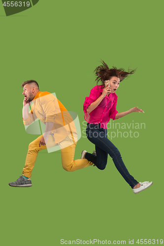 Image of Full length of young couple with mobile phone while jumping