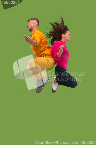 Image of Freedom in moving. Pretty young couple jumping against green background