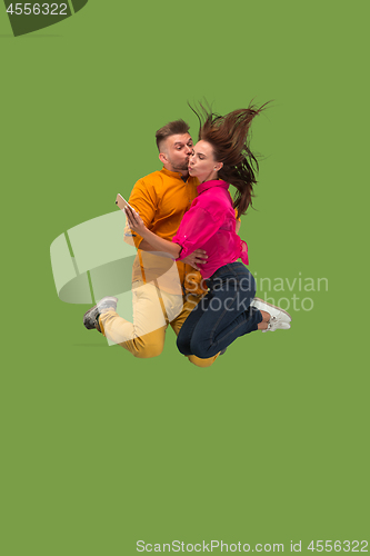 Image of Full length of young couple with mobile phone while jumping