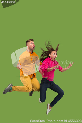 Image of Freedom in moving. Pretty young couple jumping against green background