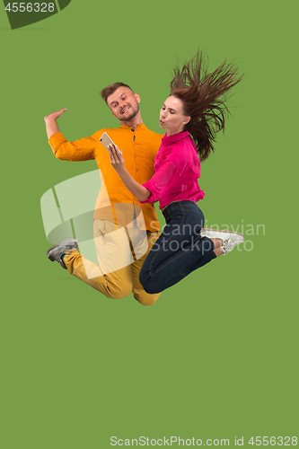 Image of Full length of young couple with mobile phone while jumping