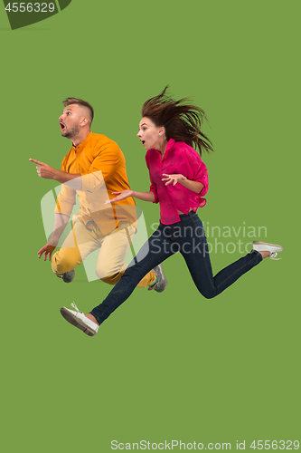 Image of Freedom in moving. Pretty young couple jumping against green background