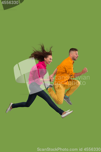 Image of Freedom in moving. Pretty young couple jumping against green background