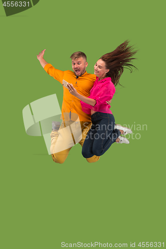 Image of Full length of young couple with mobile phone while jumping