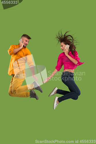 Image of Full length of young couple with mobile phone while jumping
