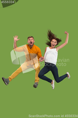 Image of Freedom in moving. Pretty young couple jumping against green background