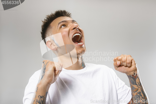 Image of The young emotional angry man screaming on gray studio background