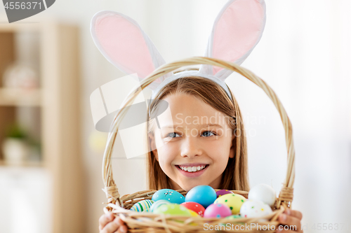 Image of happy girl with colored easter eggs at home