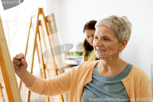 Image of senior woman drawing on easel at art school studio