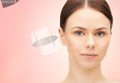 Image of face of beautiful woman over pink background