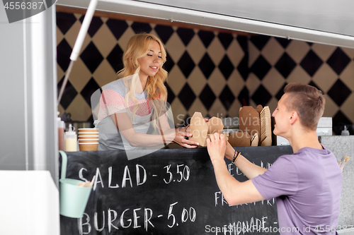 Image of saleswoman at food truck serving male customer