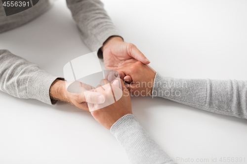 Image of close up of young woman holding senior man hands