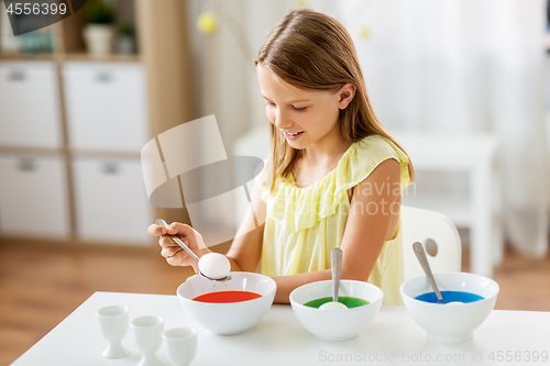 Image of girl coloring easter eggs by liquid dye at home